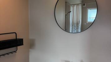 Un baño con un lavamanos blanco, un espejo redondo y un calentador de pared.