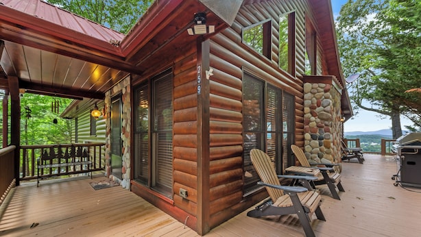 A log cabin with a porch, stone wall, and outdoor seating area. - Sunset in the Mountains – Blue Ridge, GA. (Blue Ridge)