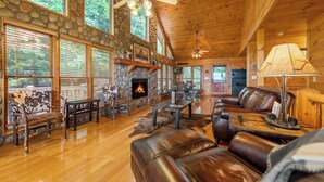A spacious living room with a stone fireplace, leather furniture, and large windows. - Sunset in the Mountains – Blue Ridge, GA. (Blue Ridge)
