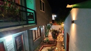 A narrow courtyard with a small garden, a water feature, and a building with a balcony. - El Rinconcito Iguazú (Puerto Iguazú)