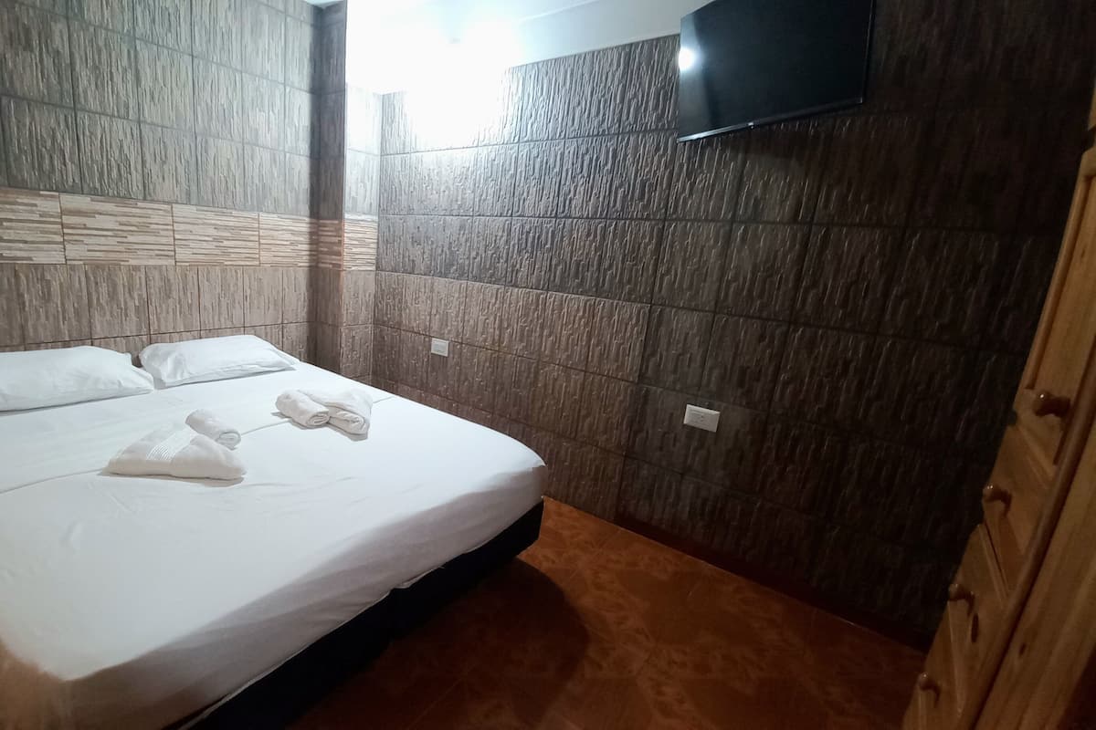 Una habitación de hotel con una cama, almohadas y toallas ordenadas.