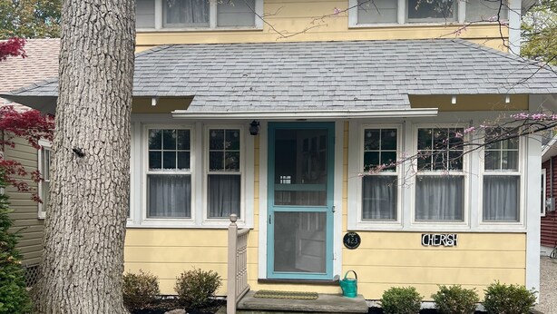 Une maison à deux étages avec une porte bleue, un petit porche avec des marches et une boîte aux lettres.