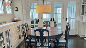 Un coin repas avec une table ronde, des chaises, un tapis à motifs et un luminaire suspendu.