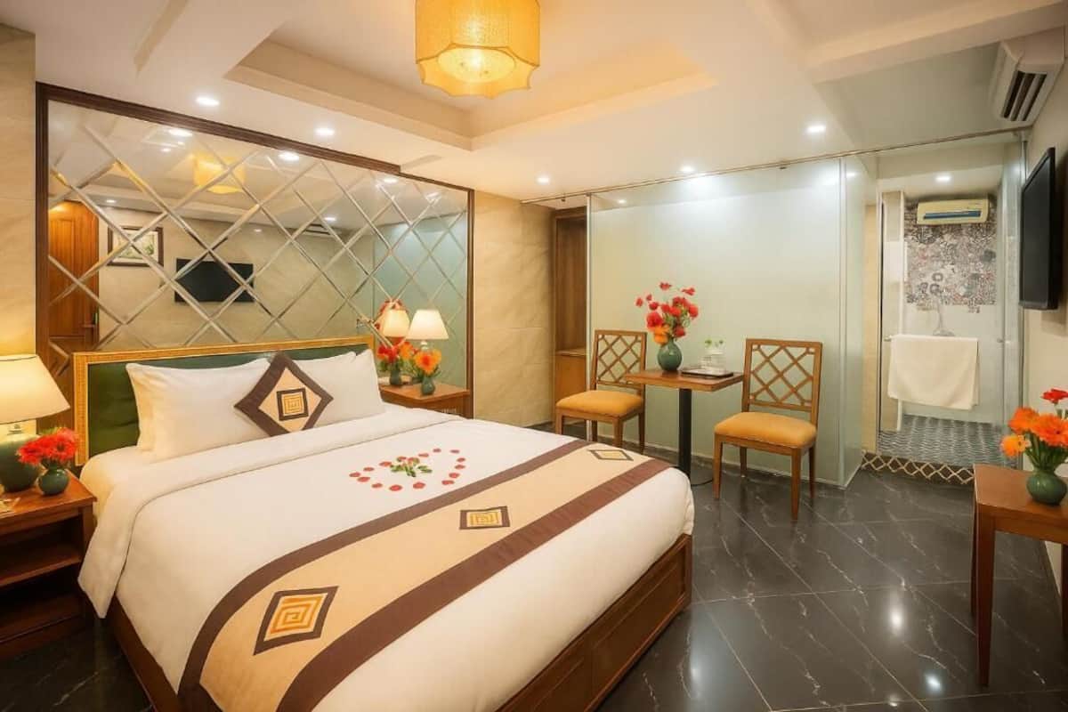 Une chambre d’hôtel avec un grand lit, un bureau, une chaise, un miroir et une télévision.