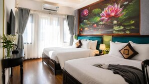 Une chambre d’hôtel avec deux lits, une grande fenêtre avec des rideaux, un tableau représentant des nénuphars et une petite table sur laquelle est posé un vase de fleurs.