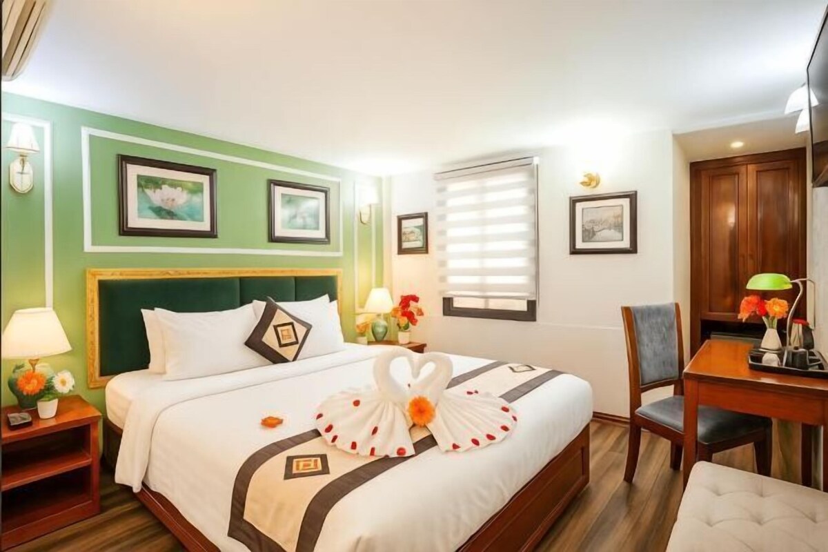 Une chambre d’hôtel avec un lit, un bureau, une chaise et une table de chevet.