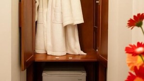 Une armoire en bois avec une tringle pour suspendre des vêtements et un petit appareil électroménager placé en dessous.