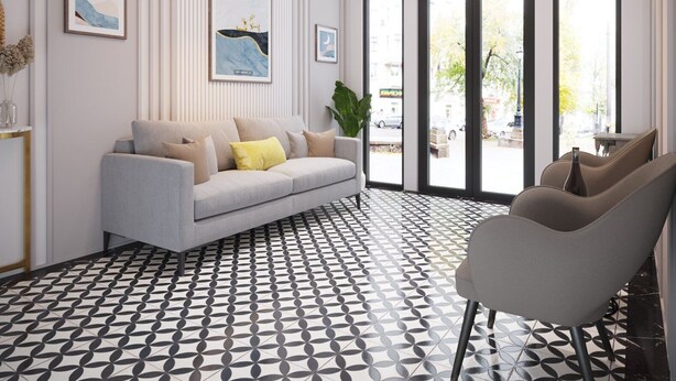 Un salon moderne avec un canapé gris, un sol à motifs et de grandes fenêtres surmontées d’arcs.