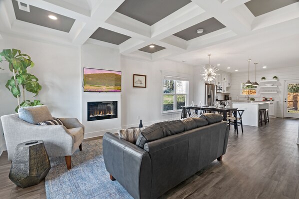 A modern living room with a fireplace, a sofa, and a dining area. - DerbyGrove: Newly Renovated & Near Derby (Jeffersonville)