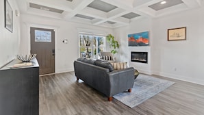 A living room with a gray sofa, a fireplace, and a large window. - DerbyGrove: Newly Renovated & Near Derby (Jeffersonville)