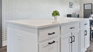 A kitchen with a white island, pendant lights, a clock, and a patterned wall. - DerbyGrove: Newly Renovated & Near Derby (Jeffersonville)