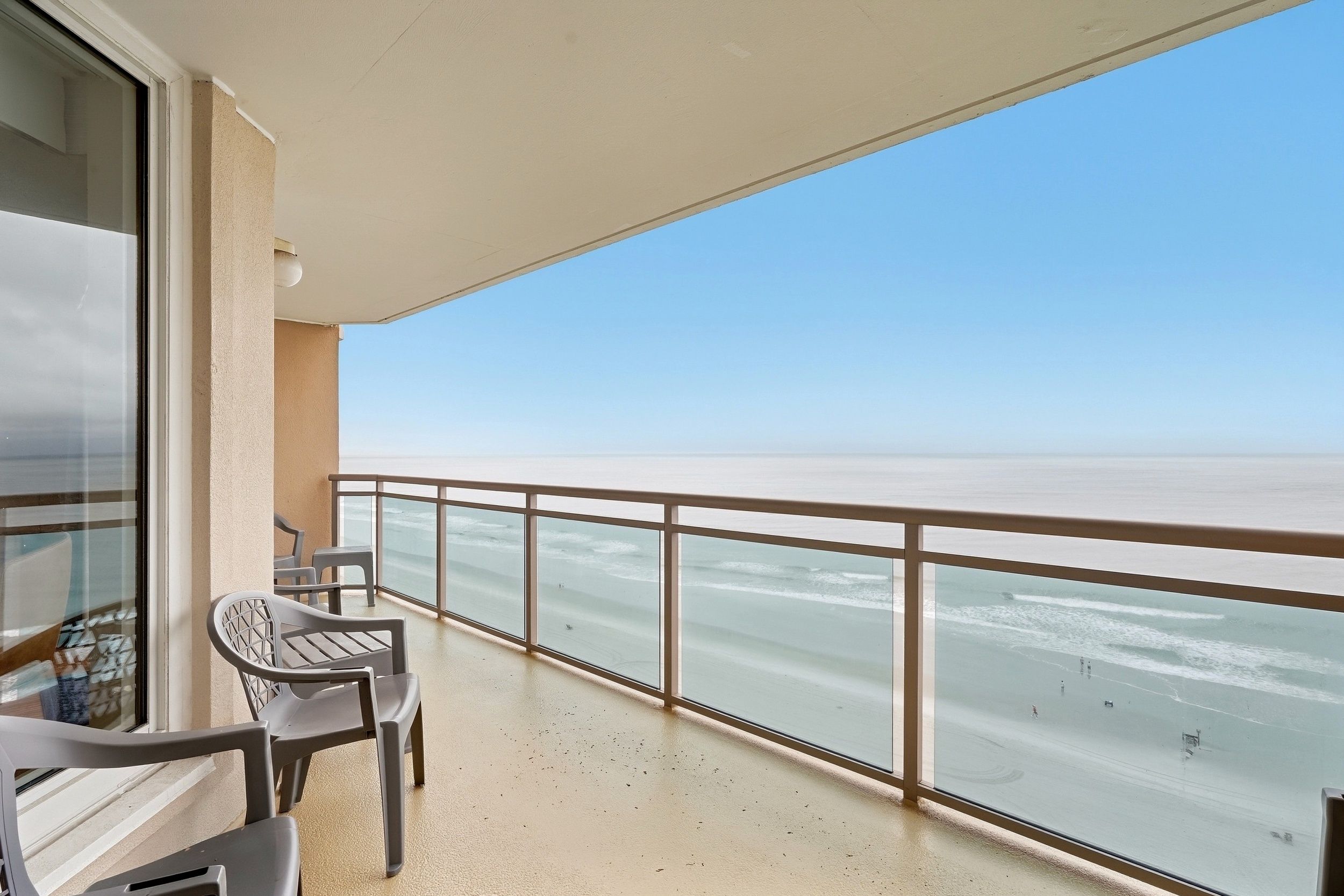 A balcony with a view of the sea, a table, and two chairs.