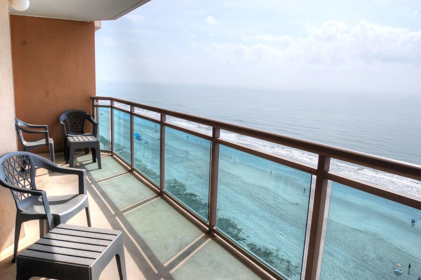 Un balcon avec vue sur la mer, équipé de chaises et d’une table en plastique.