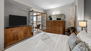 A hotel room with a large bed, a TV, a wooden dresser, a mirror, a desk, and a chair. - Condo in the Sky - Amazing Views - Gym (denver)