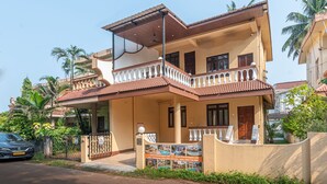 A two-story house with a balcony, a gated entrance, and a signboard. - Villa Calangute Phase 7 (Candolim)