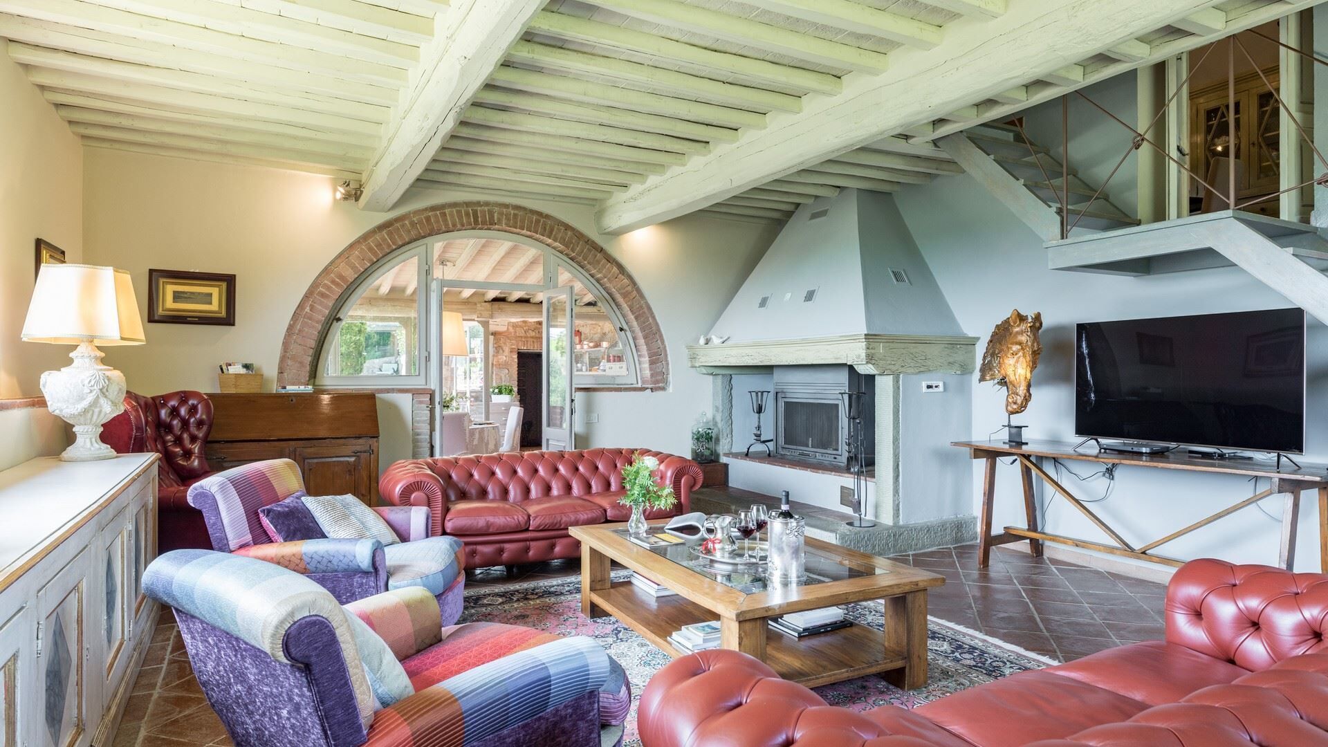 A spacious living room with a fireplace, leather sofas, and a television.