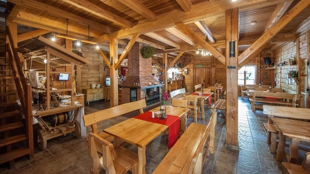A rustic wooden interior with wooden tables and benches, a fireplace, and a TV mounted on a wall. - Sport Rooms Spała (Inowlodz)