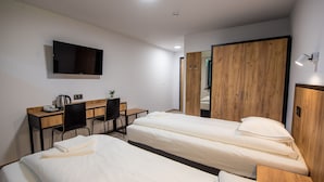 A hotel room with two single beds, a desk with a chair, a TV mounted on the wall, and a wardrobe. - Sport Rooms Spała (Inowlodz)