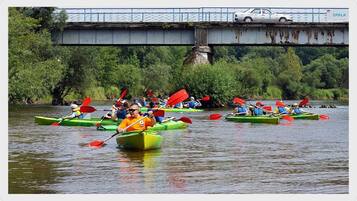 A group of people kayaking on a river under a bridge.