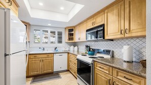 A modern kitchen with wooden cabinets, a built-in microwave, and a stainless steel oven. - Cozy Ranch-Style Condo - A Ryson Property (Palm Springs)
