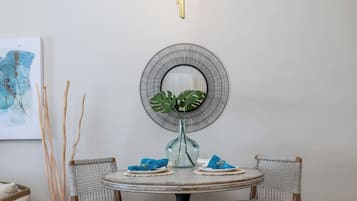 Een ronde eettafel met twee stoelen, een vaas met een plant en een spiegel aan de muur.