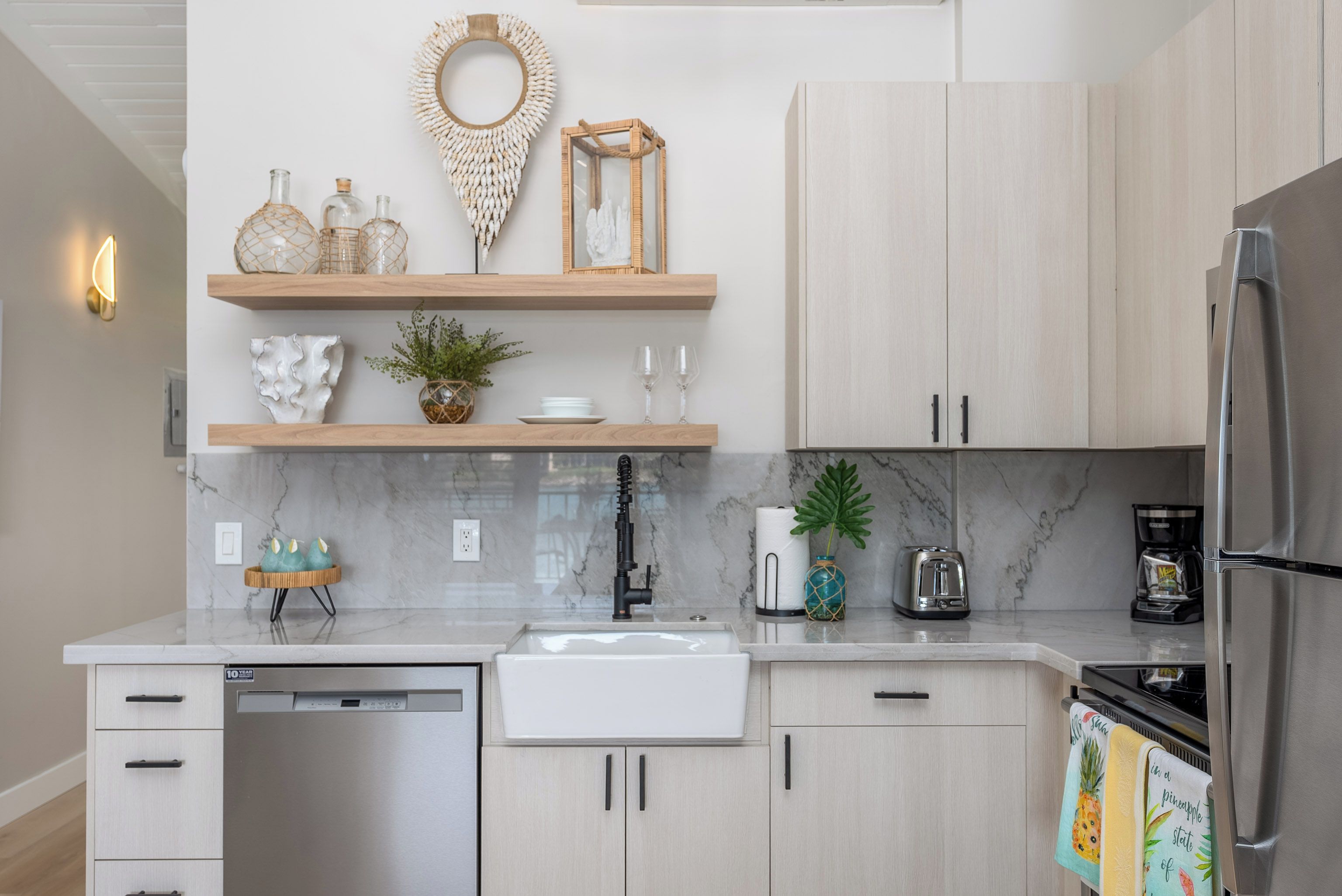 Een moderne keuken met lichte houten kastjes, een wit aanrecht en roestvrijstalen apparatuur.