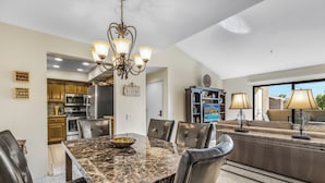 A modern kitchen with granite countertops, a dining area with a marble table, and a living area with a sofa and lamps. - Classic Comfort in Central PS - A Ryson Property (Palm Springs)