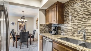 A modern kitchen with a granite countertop, stainless steel appliances, and a mosaic backsplash. - Classic Comfort in Central PS - A Ryson Property (Palm Springs)