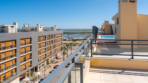 Un hotel moderno con varios pisos, piscina y vistas a la playa y al agua.