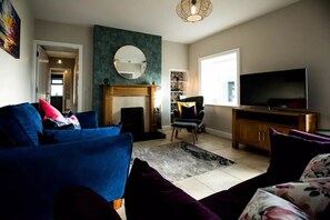 TV connectée, cheminée, livres, vidéothèque