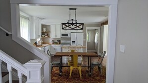 A modern kitchen with white cabinets, a wooden dining table, and a chandelier. - Restful Farm Retreat (Cincinnati)
