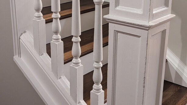 A staircase with white balusters and a wooden handrail, leading to a landing with a white door. - Restful Farm Retreat (Cincinnati)