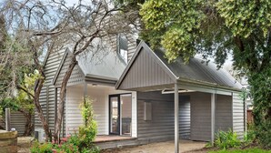 Une maison moderne dotée d’un porche abrité, d’un garage et d’un jardin bien entretenu.