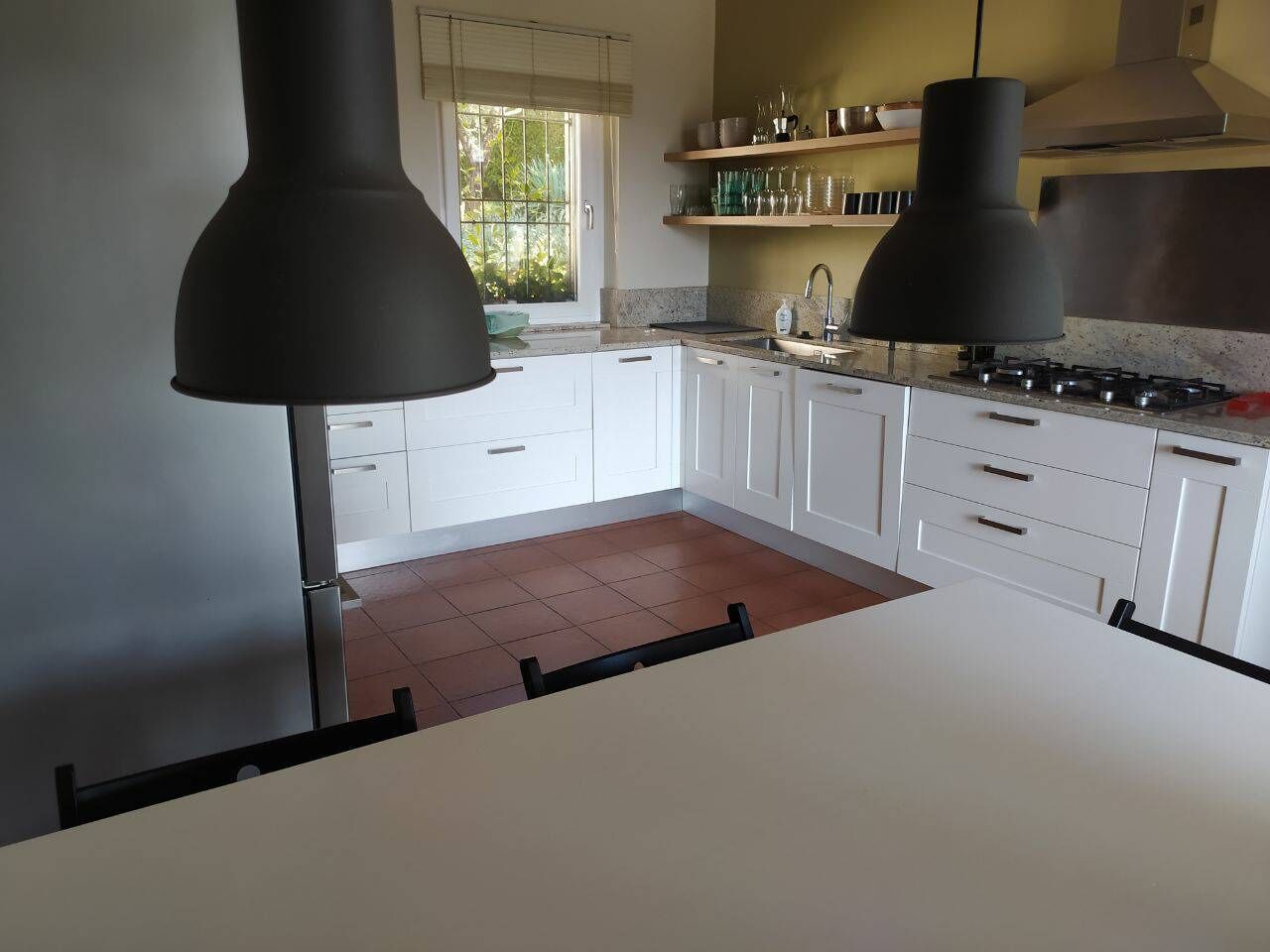 Une cuisine moderne avec des armoires blanches, une cuisinière à gaz et des luminaires suspendus.