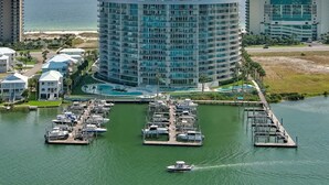 A marina with boats docked, surrounded by residential buildings and a large hotel with a curved facade. - Bella Luna 504 by Liquid Life (Orange Beach)