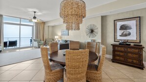 Un coin repas avec des chaises en osier, une table ronde et un luminaire décoratif au plafond.