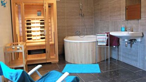 Ein modernes Badezimmer mit einer Holzsauna, einer großzügigen Badewanne und einem Waschbecken mit Spiegel.