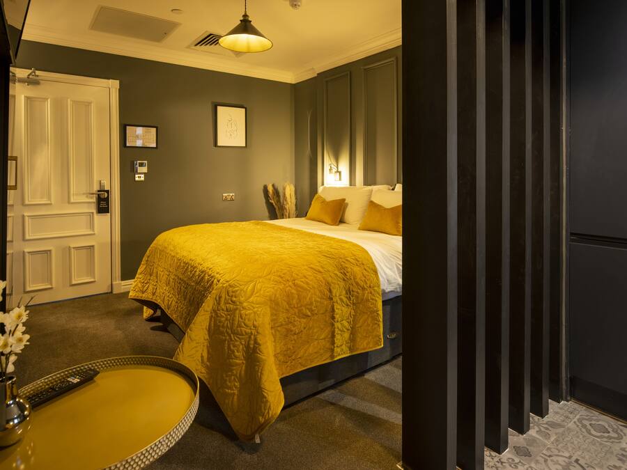 A bedroom with a bed, bedside table, and a door.
