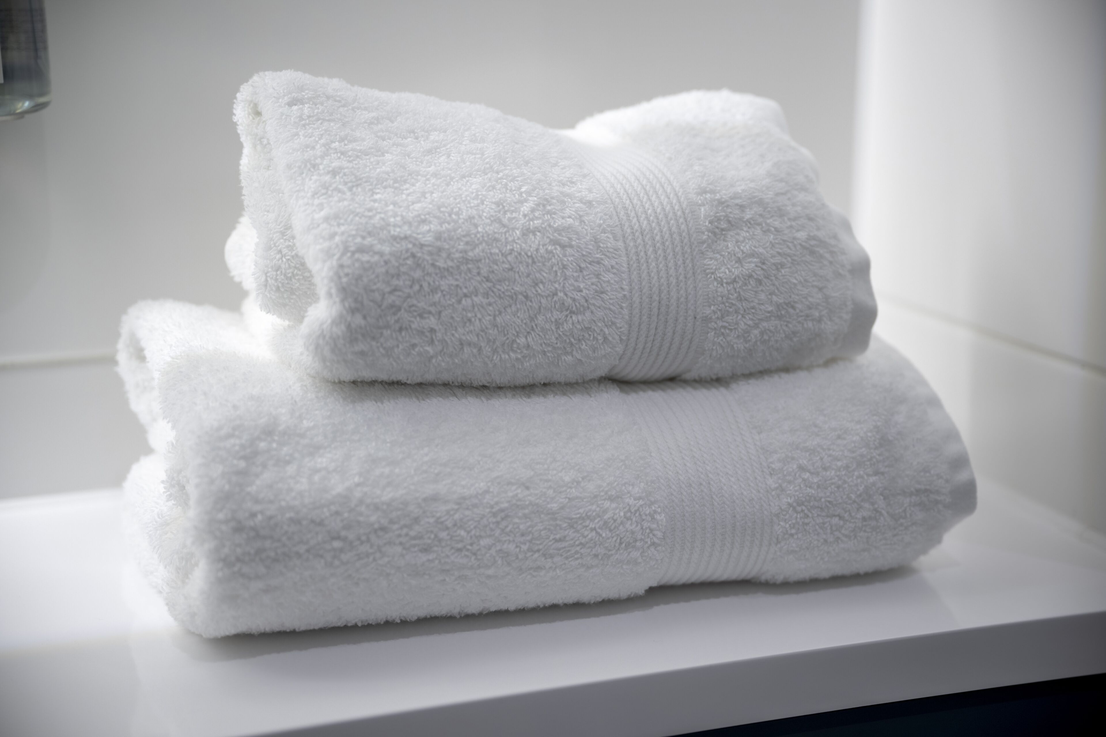 Une pile de serviettes blanches sur une surface blanche.