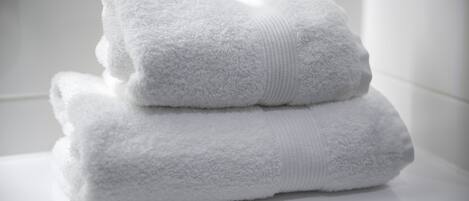 A stack of white towels on a white surface.