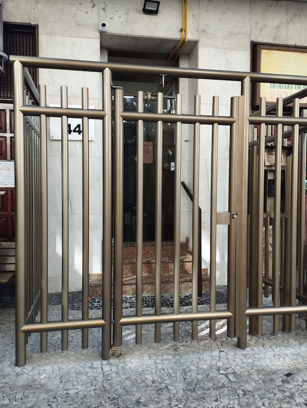 A metal gate with a number plate, leading to a building entrance.