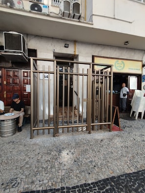 A metal gate with the number 14, a building entrance, and a tiled pavement.
