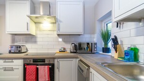 A modern kitchen with white cabinets, a dishwasher, a toaster, a kettle, and a sink. - Station Lodge By My Getaways (Brighton)
