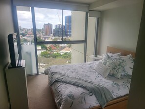 Enjoy a city view from the comfort of this stylish bedroom with a large window, a neatly made bed, and a convenient balcony access.