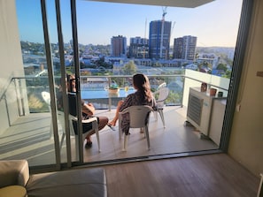 Enjoy the city view from this balcony with a glass door, small table, and two chairs.
