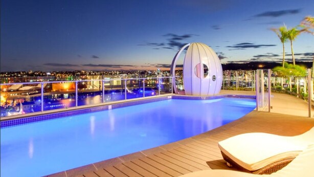 A pool with a wooden deck and a unique spherical structure. - Light apartment in amazing central location (South Brisbane)