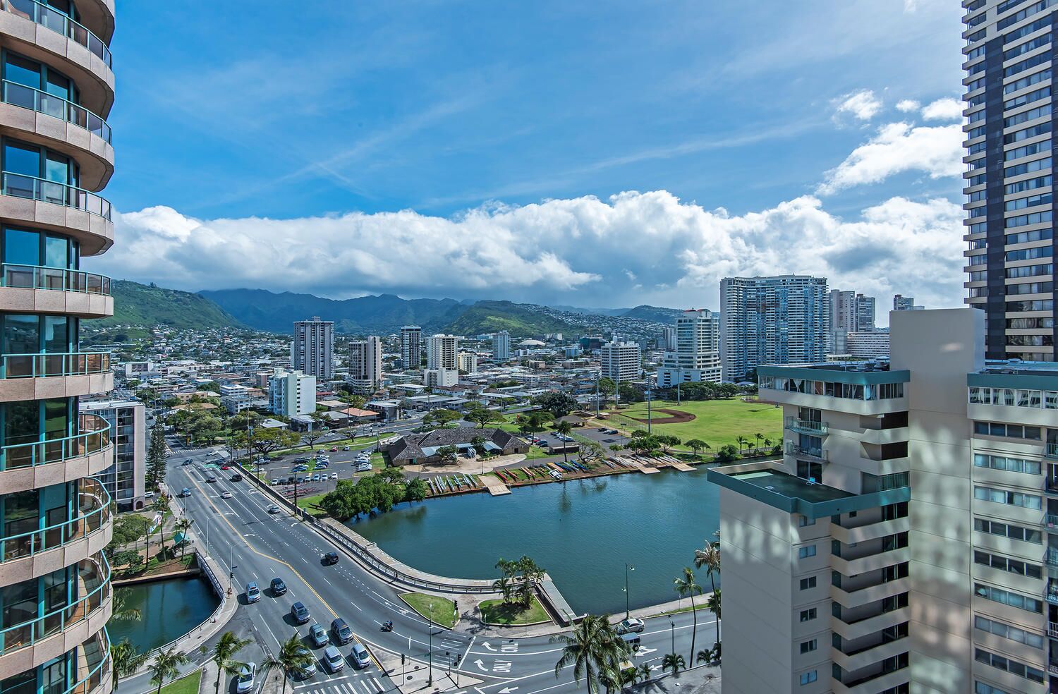 A cityscape with modern high-rise buildings, a curved road, and a body of water.