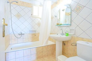 A bathroom with a bathtub, shower, sink, and toilet.