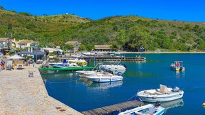 A marina with boats docked, a stone-paved waterfront, and buildings in the background. - Theophilos 2 in (Corfu)