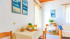 A dining area with a table set for two, a sofa, and a small table with a plant. - Theophilos 1 in (Corfu)